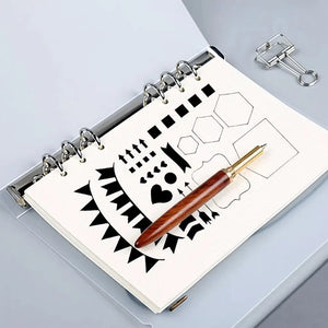 Pochoir bullet journal posé sur carnet anneaux, motifs géométriques tracés au stylo plume bois