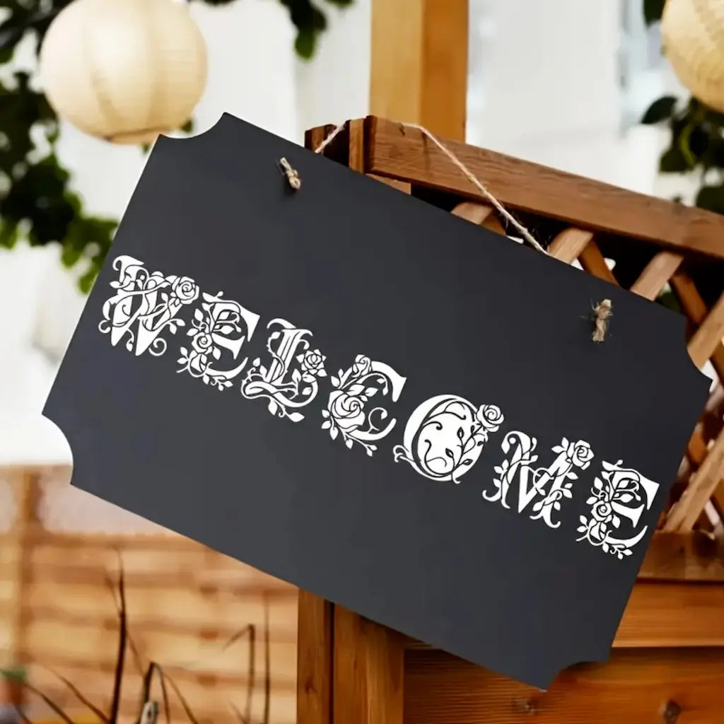Pochoir alphabet floral Welcome sur ardoise noire suspendue, lettres ornées roses et vrilles