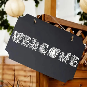Pochoir alphabet floral Welcome sur ardoise noire suspendue, lettres ornées roses et vrilles