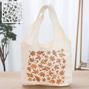Pochoir feuille d'érable tons cuivrés peint sur tote bag écru suspendu, plante en accent