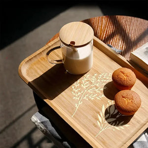 Pochoir fleur doré sur plateau bambou, mug café au lait et muffins en arrière-plan