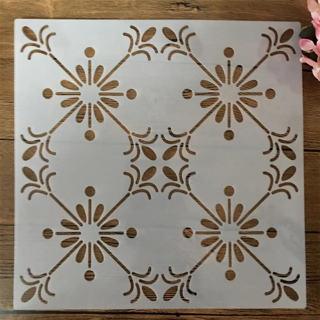 Pochoir mandala carré motif soleil quadruple répété, gouttes et pétales sur fond bois clair