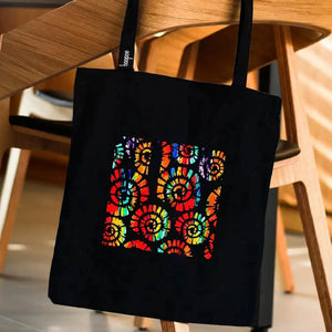 Pochoir texture spirales multicolores sur tote bag noir, motif tie-dye soleils colorés bois