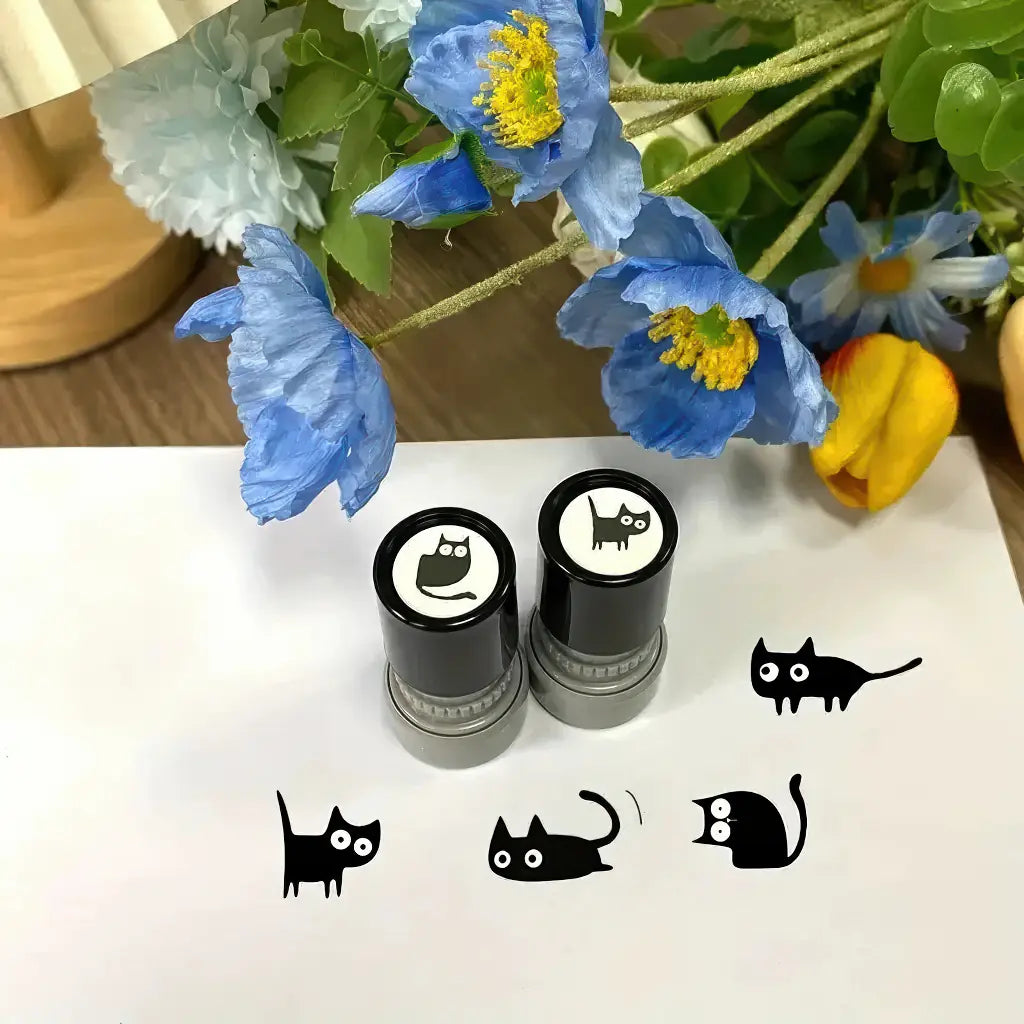 Tampons encreurs scrapbooking, deux auto-encreurs et empreintes de chats noirs sur papier